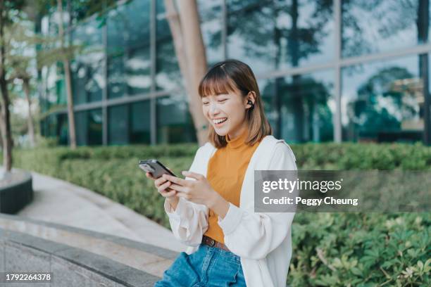 a young east asian female adult looking and using her mobile phone - asia stock pictures, royalty-free photos & images