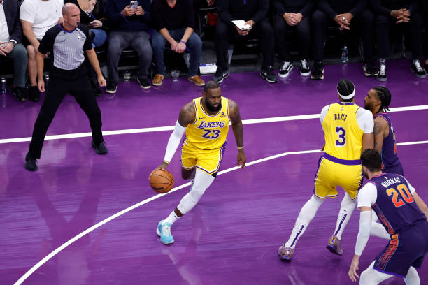 LeBron James of the Los Angeles Lakers dribbles around a screen set by Anthony Davis on Keita Bates-Diop of the Phoenix Suns during the first half of...