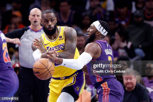 LeBron James of the Los Angeles Lakers passes around Josh Okogie of the Phoenix Suns during the first half of the In-Season Tournament game at...