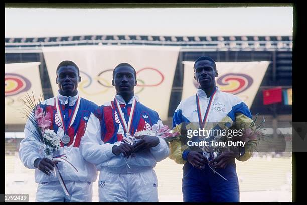 Joe Deloach and Carl Lewis of the USA pose for a picture with Robsen Da Silva of Brazil after the 200 meters during the Olympic Games in Seoul, South...