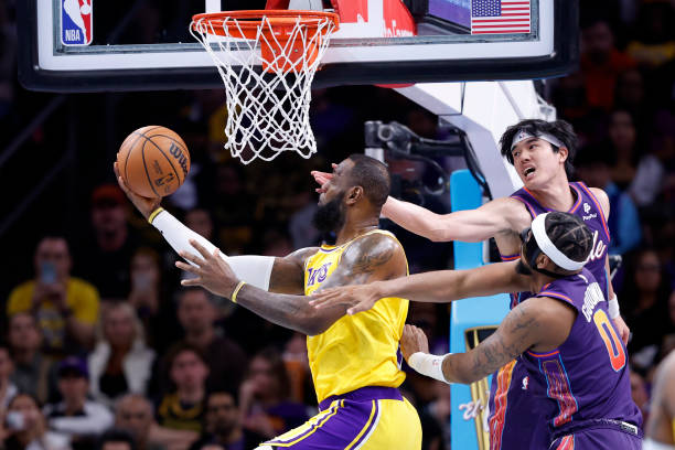 LeBron James of the Los Angeles Lakers attempts a layup against Yuta Watanabe of the Phoenix Suns and Jordan Goodwin during the first half of the...
