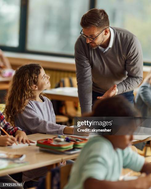 profesor masculino que asiste a la colegiala con el examen en una clase en la escuela. - male professor with students fotografías e imágenes de stock