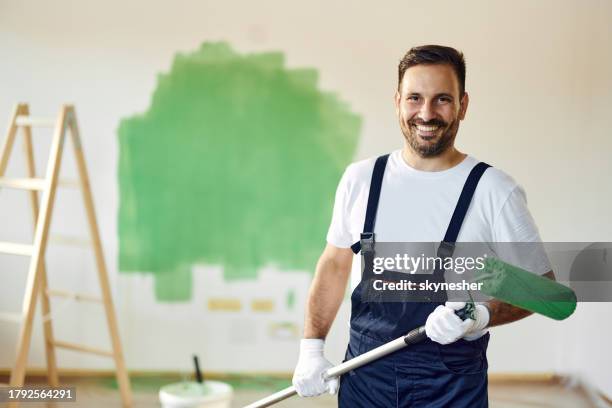 glücklicher hausmaler, der am hausrenovierungsprozess arbeitet. - anstreicher stock-fotos und bilder