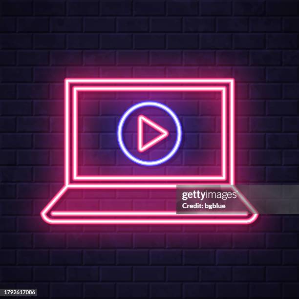 laptop with play button. glowing neon icon on brick wall background - touch screen wall stock illustrations