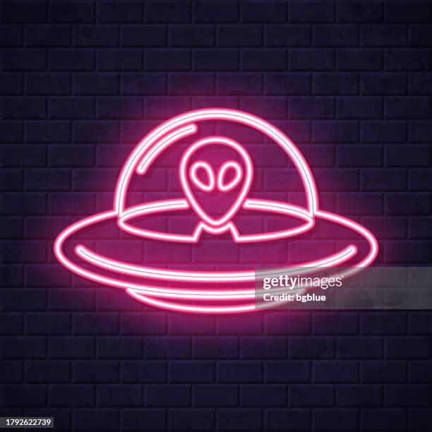 ufo - flying saucer with alien. glowing neon icon on brick wall background - video visit stock illustrations