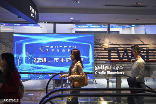 People move past a sign announcing the listing of Foxtron Vehicle Technologies Co., at the Taiwan Stock Exchange in Taipei, Taiwan, on Monday, Nov....
