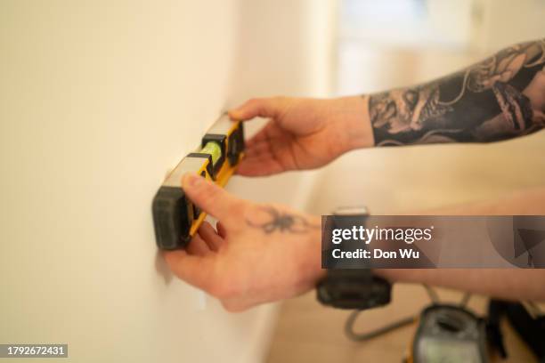 utilisation d’un niveau à bulle contre le mur - male using spirit level photos et images de collection