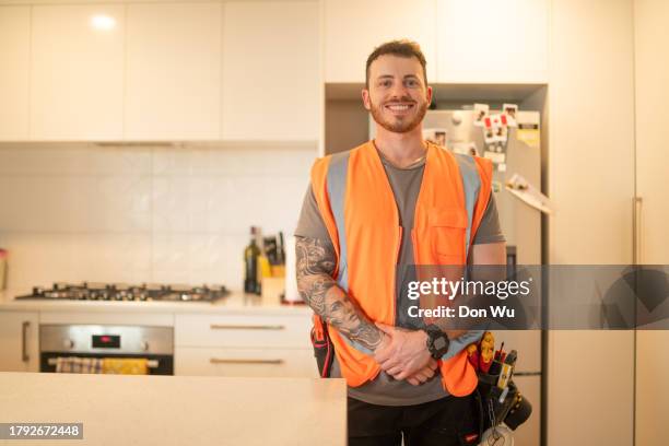 lächelnder männlicher baumeister, der in der küche steht - rohrbruch stock-fotos und bilder