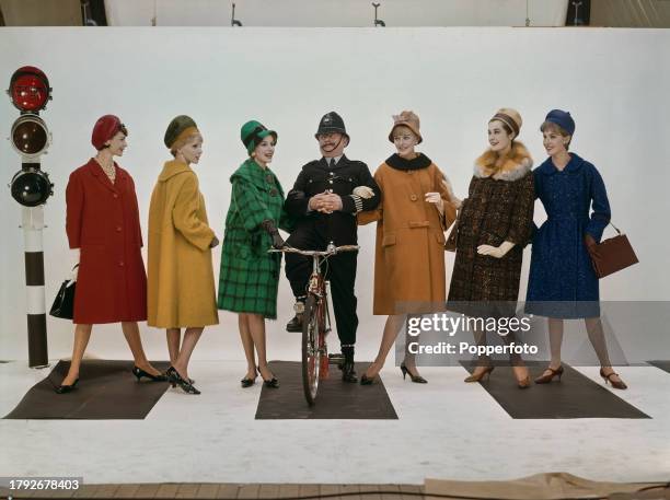 Posed studio portrait of six female fashion models wearing new winter coats in, from left, red and yellow wool, green check, orange with black fur...