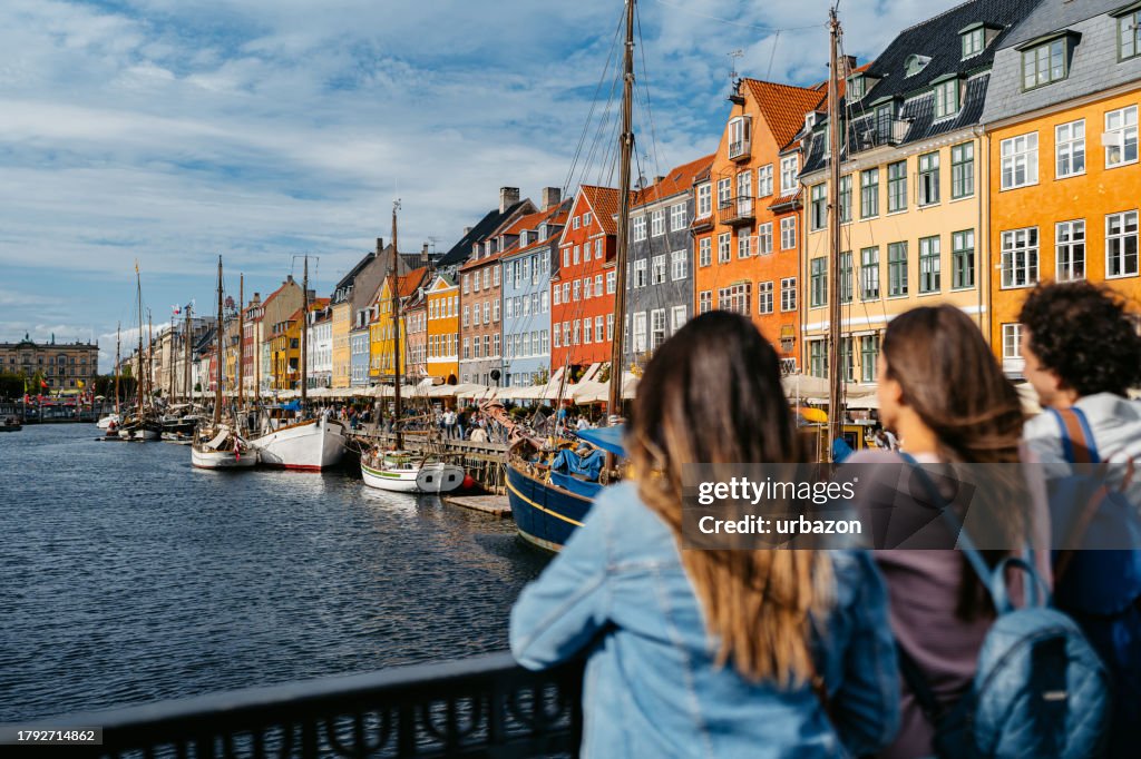 Three Young Friends Enjoying The View In Nyhavn Canal In Copenhagen In Denmark