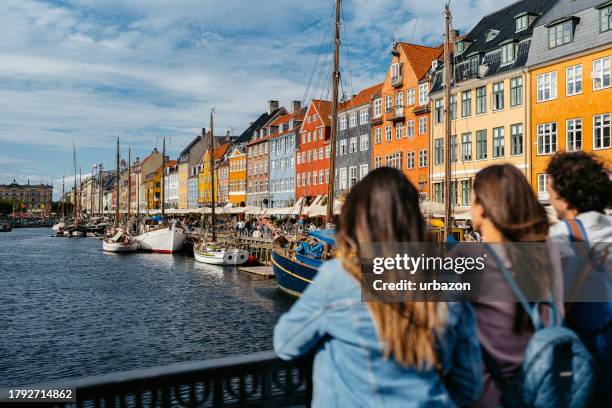 three young friends enjoying the view in nyhavn canal in copenhagen in denmark - copenhagen nyhavn stock pictures, royalty-free photos & images