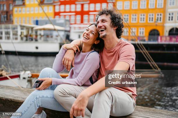 junges paar entspannt sich im nyhavn-kanal in kopenhagen in dänemark - nyhavn stock-fotos und bilder
