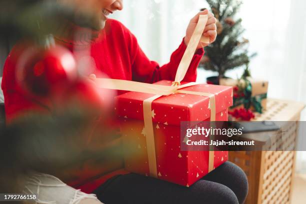 primer plano de una mujer que se divierte desata la cinta abriendo cajas de regalo el día de navidad. - desenvolver fotografías e imágenes de stock