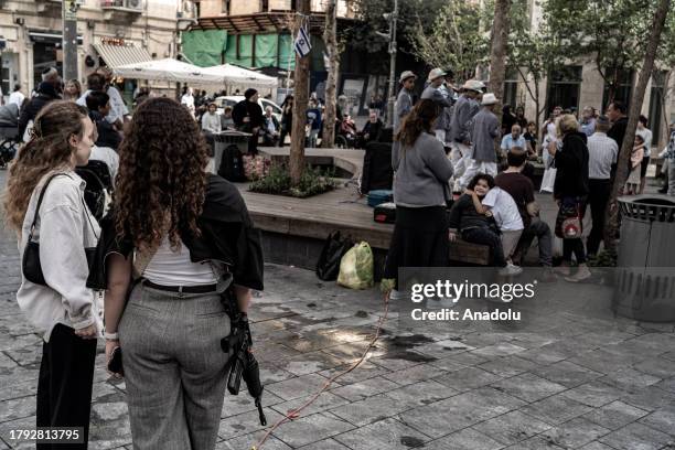 People casually walk the streets with long-barreled weapons after the Israeli government encouraged civilians to arm themselves in West Jerusalem, on...