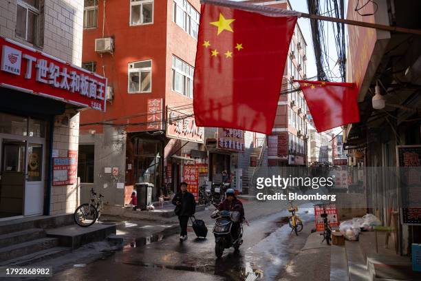 People move along the main alley of Yuxinzhuang village in Beijing, China, on Friday, Nov. 17, 2023. China home prices fell the most in eight years...