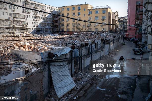 Man rides a scooter past demolished buildings in Yuxinzhuang village in Beijing, China, on Friday, Nov. 17, 2023. China home prices fell the most in...