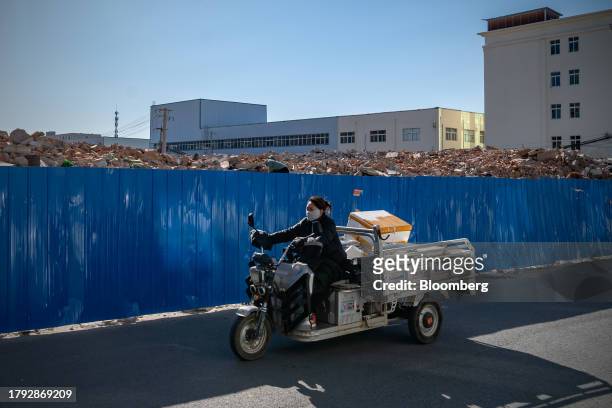 Woman rides a tricycle past demolished buildings in Yuxinzhuang village in Beijing, China, on Friday, Nov. 17, 2023. China home prices fell the most...