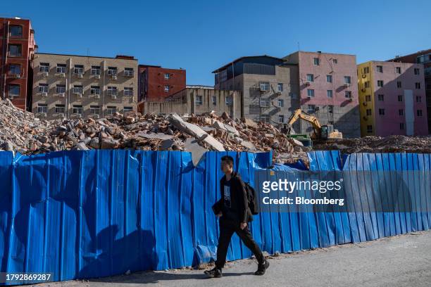 Man walks past demolished buildings in Yuxinzhuang village in Beijing, China, on Friday, Nov. 17, 2023. China home prices fell the most in eight...