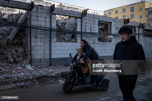 People pass by demolished buildings in Yuxinzhuang village in Beijing, China, on Friday, Nov. 17, 2023. China home prices fell the most in eight...