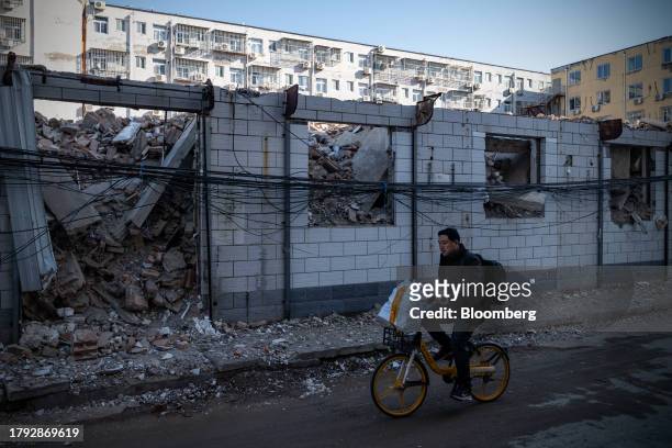 Man rides a bicycle past demolished buildings in Yuxinzhuang village in Beijing, China, on Friday, Nov. 17, 2023. China home prices fell the most in...