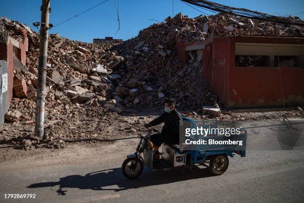 Man rides a tricycle past demolished buildings in Yuxinzhuang village in Beijing, China, on Friday, Nov. 17, 2023. China home prices fell the most in...