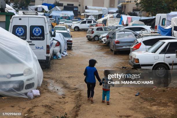 Displaced Palestinian children who fled the northern Gaza Strip due to Israeli bombardment, walk on the grounds of the Nasser Hospital where they are...