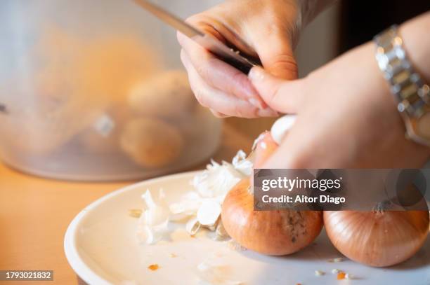a woman cuts onions to cook something. - haushaltsmesser stock-fotos und bilder