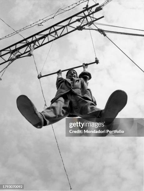 Clown in a suburban circus trains by doing trapeze acts. Milan , 1950 SPECIAL FEE - CONTACT US FOR EVERY USAGE