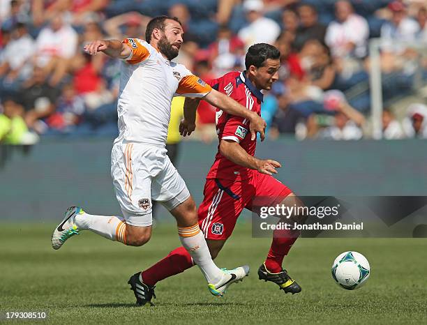 Dilly Duka of the Chicago Fire controls the ball under pressure from Adam Moffat of the Houston Dynamo during an MLS match at Toyota Park on...