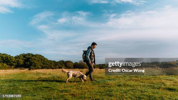 young asian man walking in nature with his dog - marches photos et images de collection