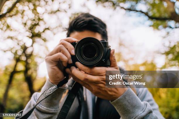 man using a dslr camera in a forest in autumn - paparazzi photographer imagens e fotografias de stock