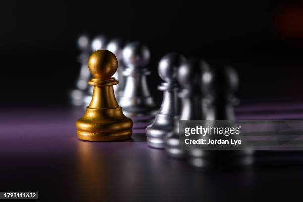 gold pawn standing out from the crowd - pawn chess piece - fotografias e filmes do acervo