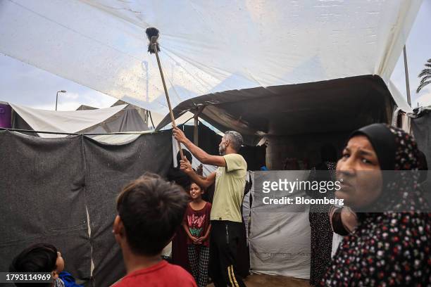 Man clears rainwater from a plastic roof shelter in a camp for displaced Palestinians near the Shuhada Al-Aqsa hospital in Deir al-Balah, Gaza, on...