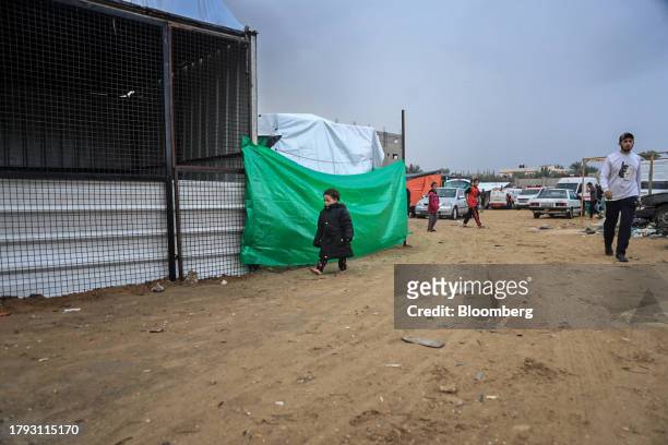 Child walks past a temporary shelter in a camp for displaced Palestinians near the Shuhada Al-Aqsa hospital in Deir al-Balah, Gaza, on Monday, Nov....