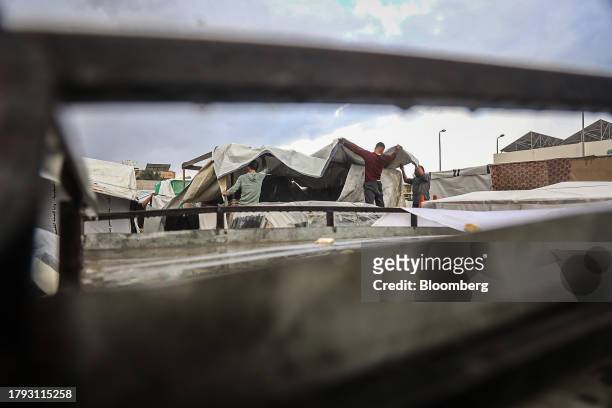 Men build temporary shelters in the rain in a camp for displaced Palestinians near the Shuhada Al-Aqsa hospital in Deir al-Balah, Gaza, on Monday,...