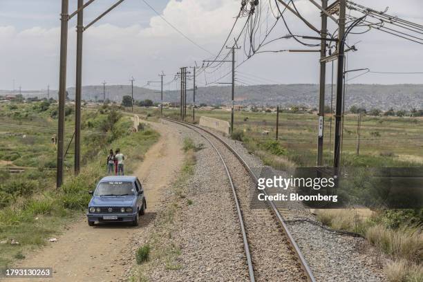 Classic Volkswagen AG Golf automobile drives down a dirt track alongside the central corridor rail freight line, between Sentrarand depot and Pyramid...