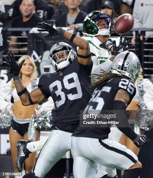 Cornerback Nate Hobbs and safety Tre'von Moehrig of the Las Vegas Raiders break up a pass to wide receiver Garrett Wilson of the New York Jets in the...