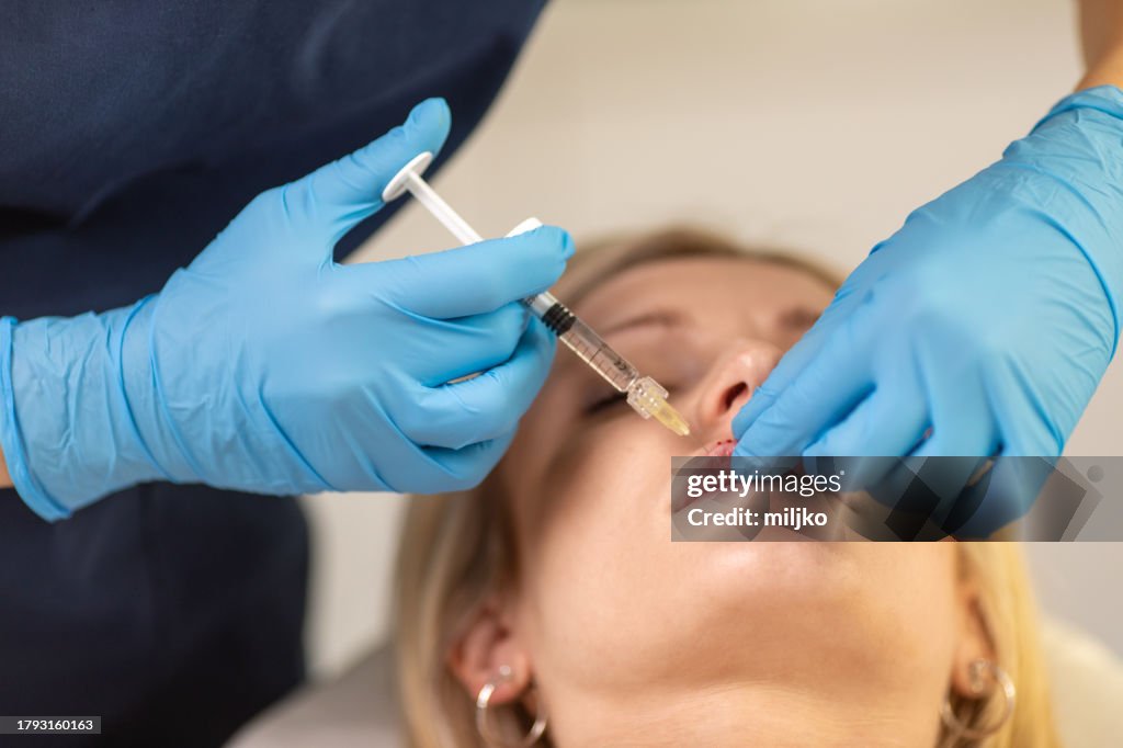 Young woman having hyaluronic lip treatment