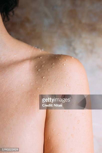 close up view of woman shoulder with water droplets - over the shoulder view stockfoto's en -beelden