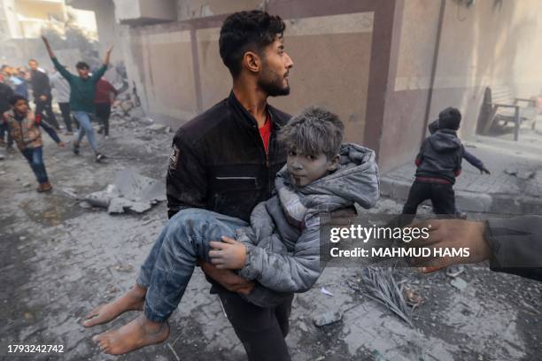 Man carries a child injured in an Israeli strike on Rafah in the southern Gaza Strip on November 20 amid continuing battles between Israel and the...
