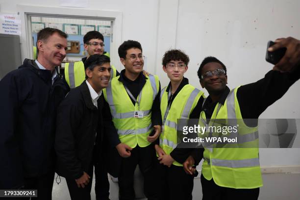 Britain's Prime Minister Rishi Sunak and Britain's Chancellor of the Exchequer Jeremy Hunt pose for a group selfie with apprentices during a visit to...