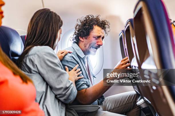 male passenger having a panic attack on airplane flight - man flying stockfoto's en -beelden
