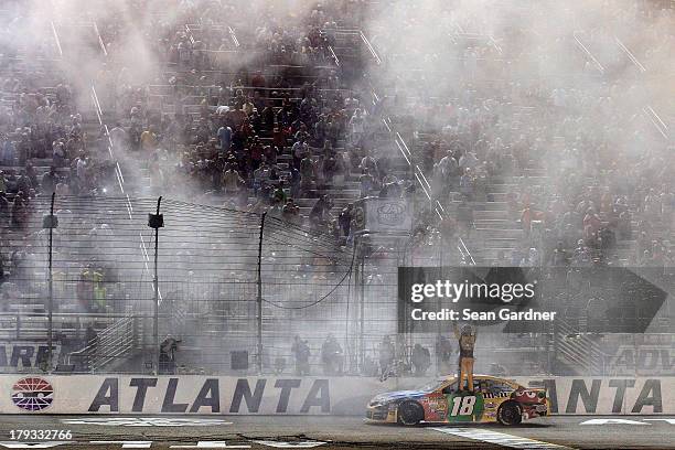 Kyle Busch, driver of the M&M's Toyota, celebrates after winning the NASCAR Sprint Cup Series AdvoCare 500 at Atlanta Motor Speedway on September 1,...