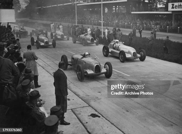 Spectators in the grandstand look on as pole sitter Hans Stuck from Germany, driver of the Auto Union AG Auto Union Type B and compatriot Rudolf...