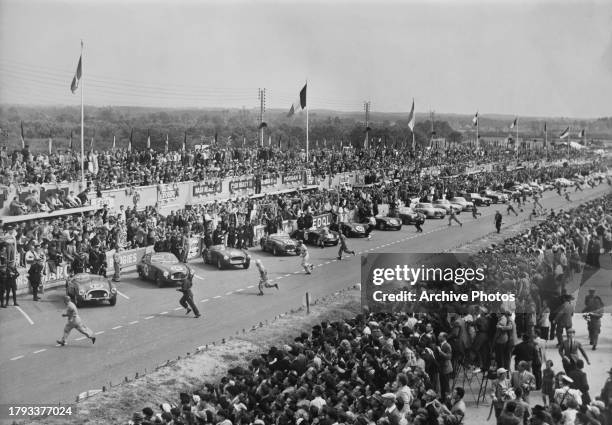 Spectators in the grandstand look as the drivers of the, #14, #16 Luigi Chinetti and Ecurie Rosier entered Ferrari 340 America sports cars run across...