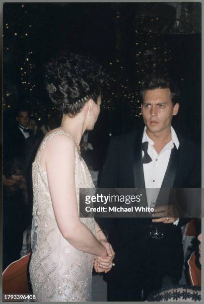 Johnny Depp with loose black tie talking to Andy McDowell , circa 1995.