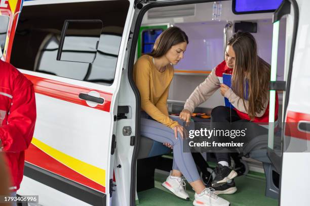 emergency healthcare worker providing first aid to injured woman in ambulance - injured nurse stock pictures, royalty-free photos & images