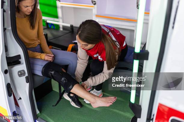emergency healthcare worker providing first aid to injured woman in ambulance - injured nurse stock pictures, royalty-free photos & images