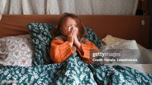 cozy recovery: child in bed with sweater, using tissue during cold season. - maladie photos et images de collection
