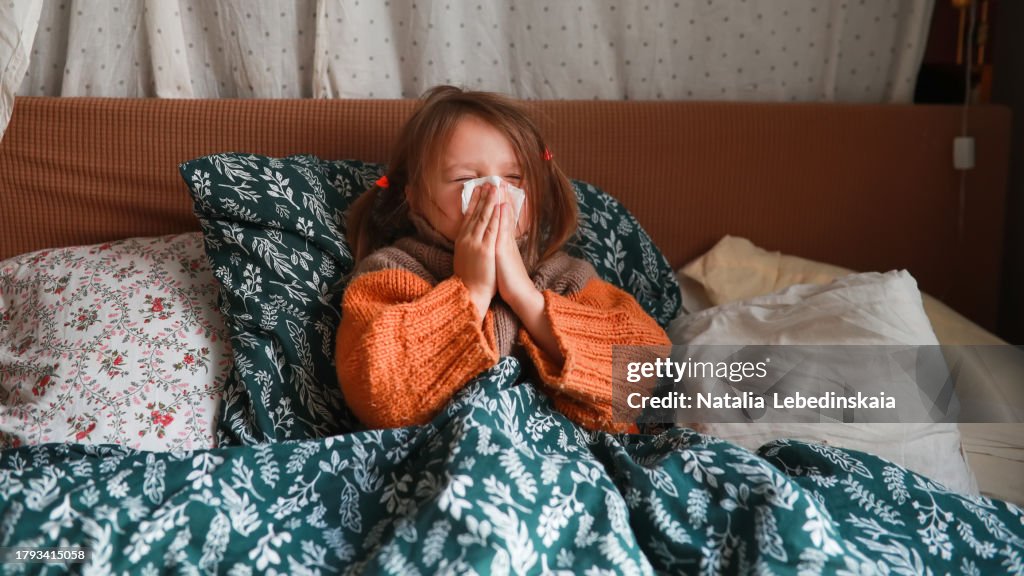 Cozy Recovery: Child in Bed with Sweater, Using Tissue During Cold Season.